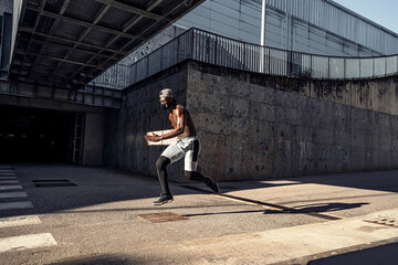 Fototapeta na wymiar Athletic black man is training in urban area while wearing a mask.