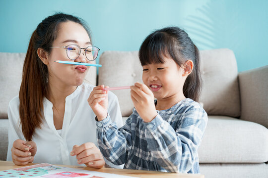  happy Asian family with mother and daughter sitting playing enjoying and activity together 