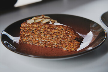 Waffle cake with boiled condensed milk decorated with almonds. Dessert at the cafe in the plate. Dulce de leche filling.