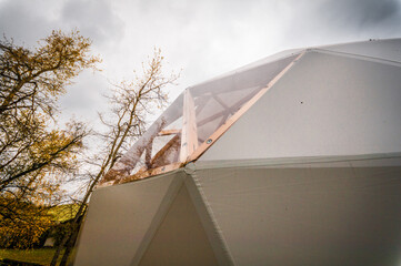 Large geodesic dome tent in autumn forest. Modern outdoor glamping tent on meadow.