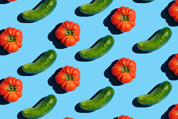 Flat lay of beautiful trendy seamless pattern tomato and cucumber. Pattern of red tomatoes and green cucumbers on a blue background. Vegans concept. Suitable for posters, packaging, postcards