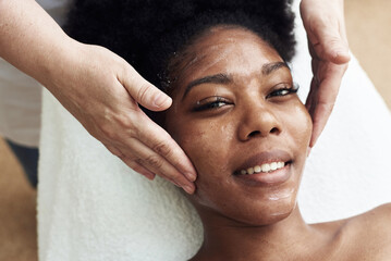Smiling black woman enjoying a toning facial massage. Serene woman relaxing outdoor in a beauty...