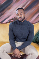 Pensive handsome black man sitting on a couch