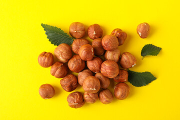Tasty hazelnuts and leaves on yellow background. Vitamin food