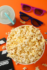 Composition with bucket of popcorn on orange background. Food for watching cinema