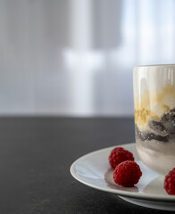 Cup, plate and redberries on dark stone table for break concept in healthy lifestyle and eating with copy space