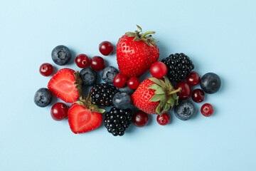 Mix of fresh berries on blue background, top view