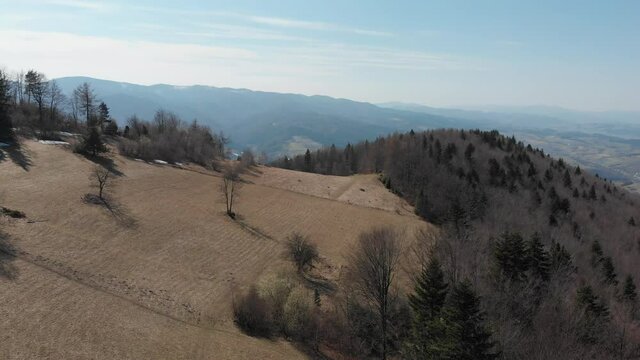 Flying from Makowica Mount in Beskids Mountains towards Rytro Village in early spring. Poland.