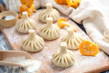 Uncooked Georgian dumplings or khinkali with mushrooms and pork on a wooden cutting Board