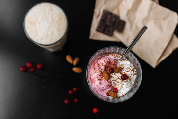 ice cream white and pink in a transparent cream bowl with nuts and berries on a black table