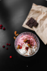 ice cream white and pink in a transparent cream bowl with nuts and berries on a black table