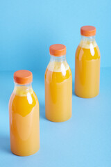 Freshly squeezed orange juice in  bottle on blue background. 