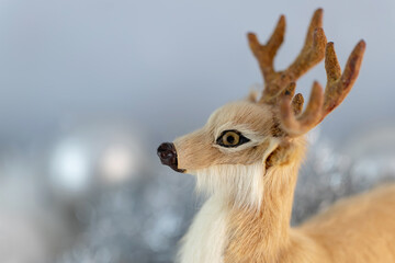 Toy Christmas deer on a background of silvery decorations