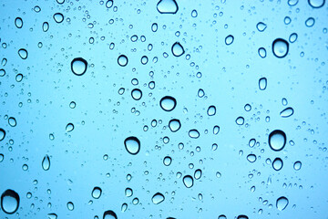 Drops of water on car glass, rain drops on clear window and blue background.