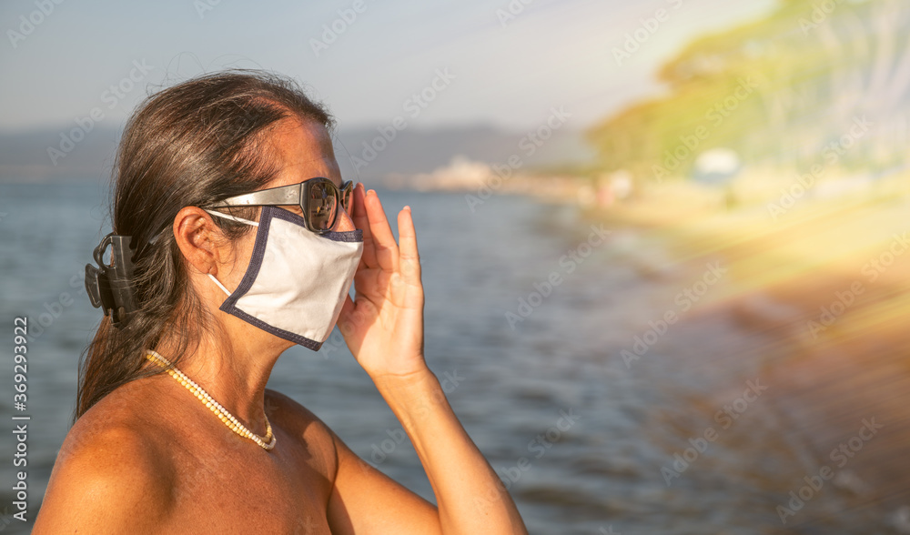 Canvas Prints Woman walking on the beach wearing mask in coronavirus times