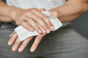 Detail Aufnahme einer Person, die sich mit einem Hygienetuch die Hände reinigt und desinfiziert