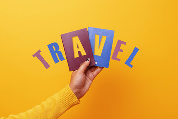 Hand holding two passports with inscription travel over yellow background