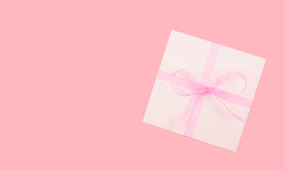 Top view, greeting card with place for text. Gift box with a bow on a pink background.