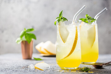 Melon juice, lemonade in glasses with ice and melon slices garnished with basil leaves. Concept of fresh summer drink - obrazy, fototapety, plakaty