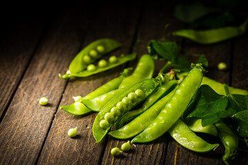 Pods of green peas on a old wooden background close up, soft focus