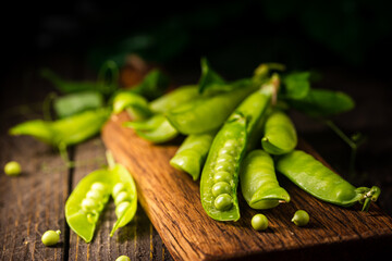 Pods of green peas on a old wooden background close up, soft focus