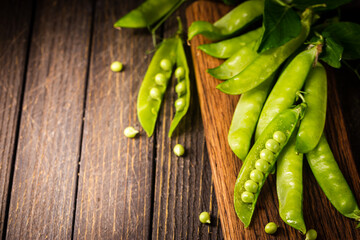 Pods of green peas on a old wooden background close up, soft focus