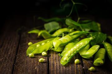 Pods of green peas on a old wooden background close up, soft focus