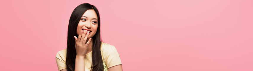 website header of happy young asian woman covering mouth isolated on pink