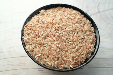 raw brown rice on wooden background top down.