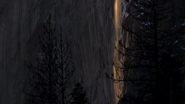 Tilt up shot of Firefall-- seasonal Horsetail Falls illuminated by evening sunlight in Yosemite National Park, California