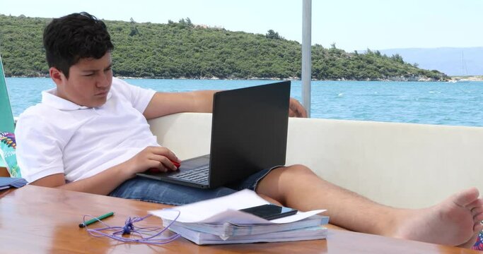 Teenage boy studying on yacht deck Online learning education distance learning for kids at home Homeschooling during quarantine or isolation