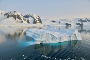 Fototapeta na wymiar Iceberg reflection, calm blue ice water, soft evening light, glacier, Antarctica