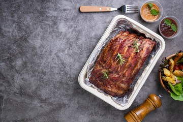 Grilled pork ribs with Vegetables and sauces on a drak table