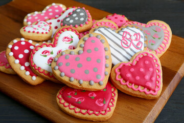 Homemade lovely patterned heart shaped royal icing cookies on  wooden breadboard