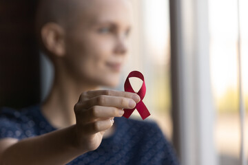 Crop close up of sick woman hold red ribbon symbol of oncology show support and awareness of...