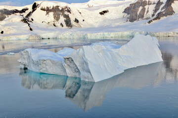Iceberg reflection, blue ice water, peaceful evening sunset, glacier, Antarctica