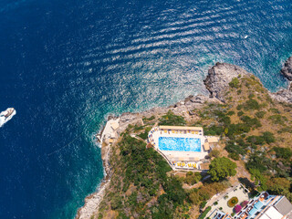 Aerial top view. Villa with a swimming pool by the sea. Steep rocky shore. Tourism and vacation concept. The motor boat moves fast. Hotel. Tour to the ocean. Europe Italy