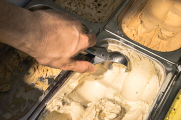 close up of a hand of a seller making vanilla ice cream scoop, hot summer weather refreshment snack