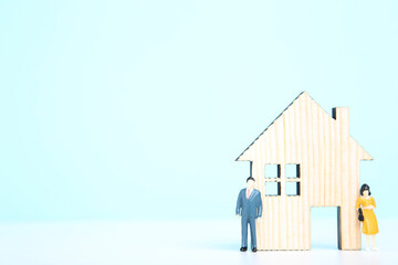 Wooden house model with miniature people on blue background