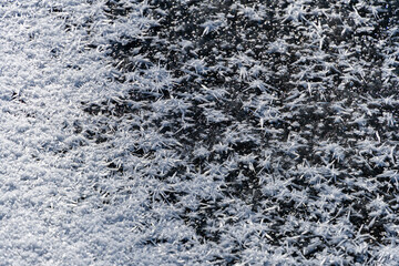 Natural ice structure on surface of frozen and snow-covered pond. Beautiful ice patterns are covered with snow. Close-up. Snowflakes on icy surface of the pond. Nature concept for winter design.