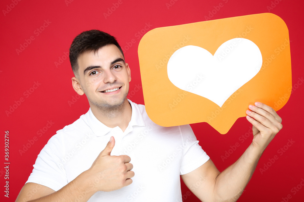 Sticker Young man holding paper heart on red background