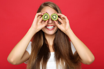 Young girl holding kiwi fruit on red background