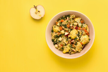Summer salad with cauliflower, quinoa, apple and parsley on a yellow background. Copy space