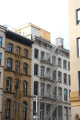 Beautiful Old Apartment Building Exterior with a Fire Escape, Red-brick, grey and beige, in Manhattan, New York City, USA, America.