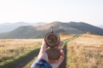Man with old metal compass in hand on mountains road. Travel concept. Landscape photography - obrazy, fototapety, plakaty