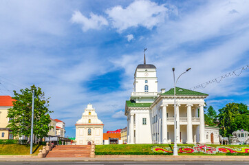 Town Hall building on Freedom Svabody square and Church of St. Joseph in Upper Town Minsk historical city centre, blue sky white clouds in sunny summer day, Republic of Belarus