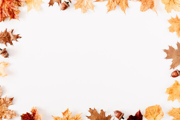 Autumn creative composition. Frame made of dry leaves, acorns on white background. Fall concept....