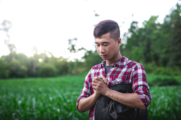 Young male standing and praying in corn field. belief of agriculture concept.