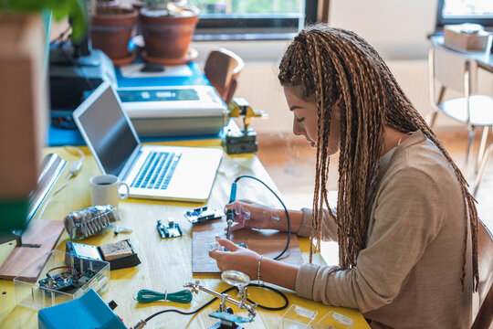 Woman electronics engineer is soldering circuit  board in her workshop stock photo