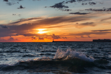 Fototapeta premium Beautiful sunset on the embankment of Sevastopol (Crimea). The sun sets in the sea. Very beautiful seascape, view of the sea, waves and sky with clouds.